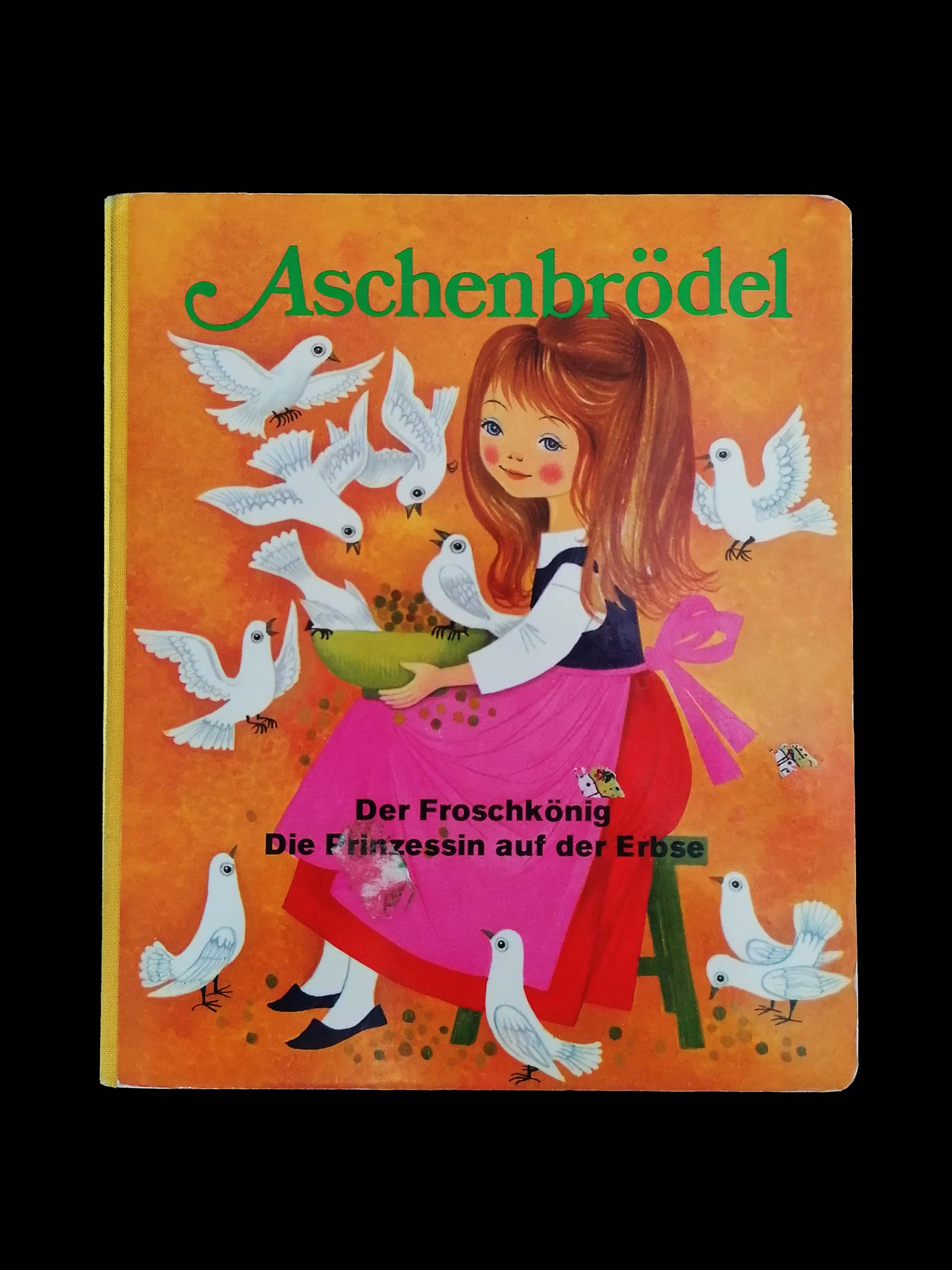 Ein kleines Buch, auf dessen Cover Aschenbrödel sitzt mit einer Schale Linsen in der Hand, die die Tauben für sie sortieren. Geschrieben steht "Aschenbrödel, der Froschkönig, Die Prinzessin auf der Erbse"