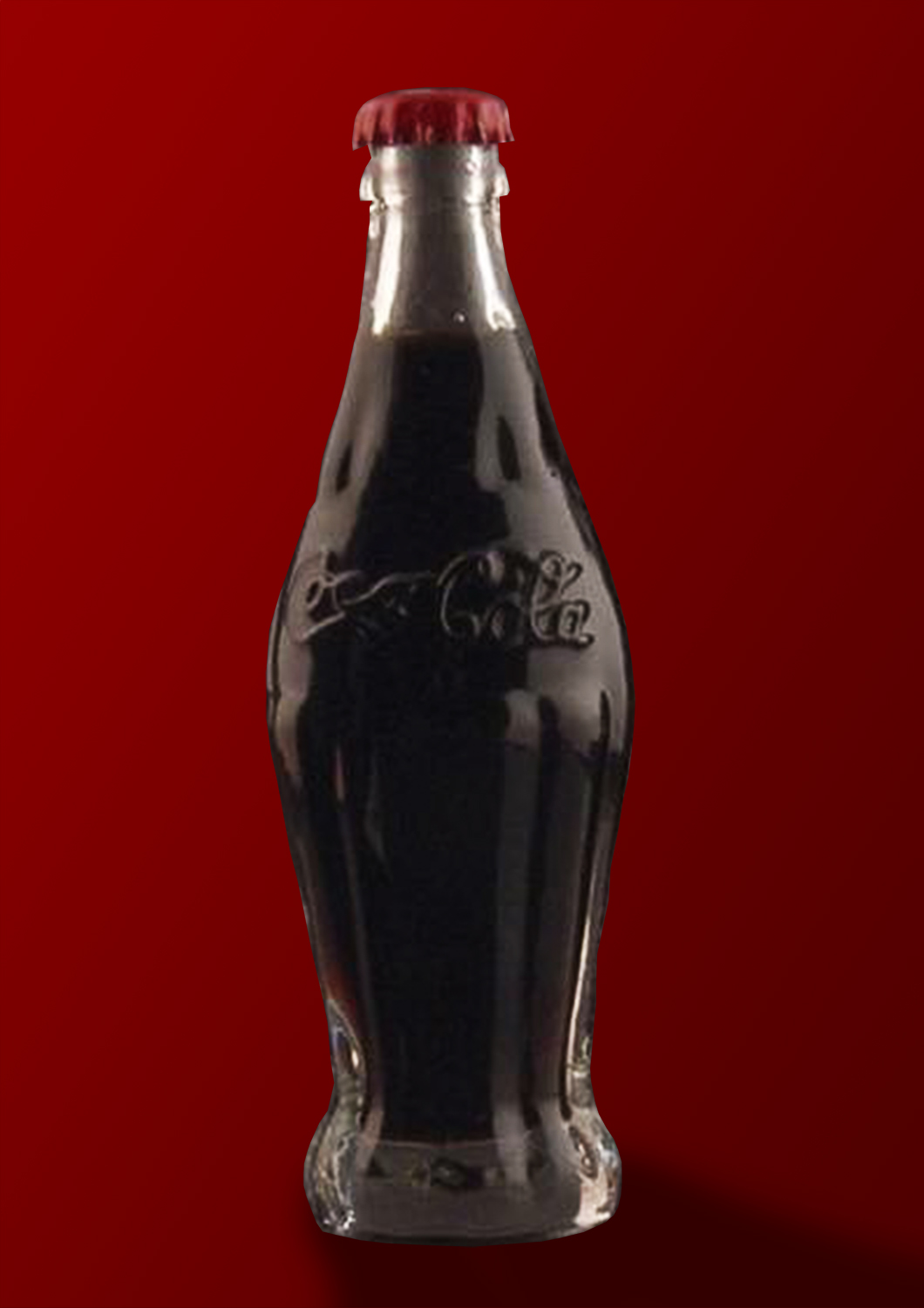 Eine Coca Cola Flasche aus dem Jahre 1915 vor rotem Hintergrund.